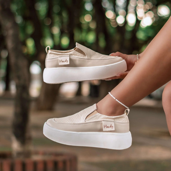 Mocasín beige para mujer con diseño moderno y cómodo, suela blanca gruesa antideslizante, material flexible que brinda soporte y estilo casual ideal para uso diario en ciudad y oficina.