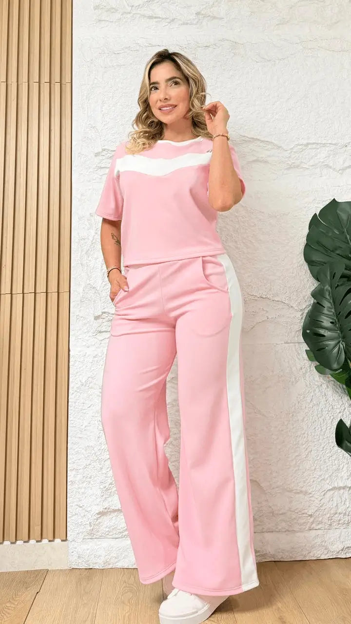Conjunto combinado femenino en rosa con franjas blancas, top crop de manga corta y pantalón ancho con bolsillos laterales, confeccionado en tela suave, elástica y transpirable que brinda comodidad y libertad de movimiento para un look casual y deportivo.