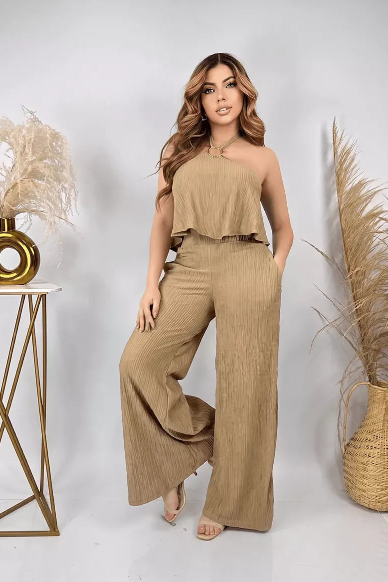 Enterizo Alexa de color beige en tela plisada con cuello halter y pantalón de pierna ancha.
