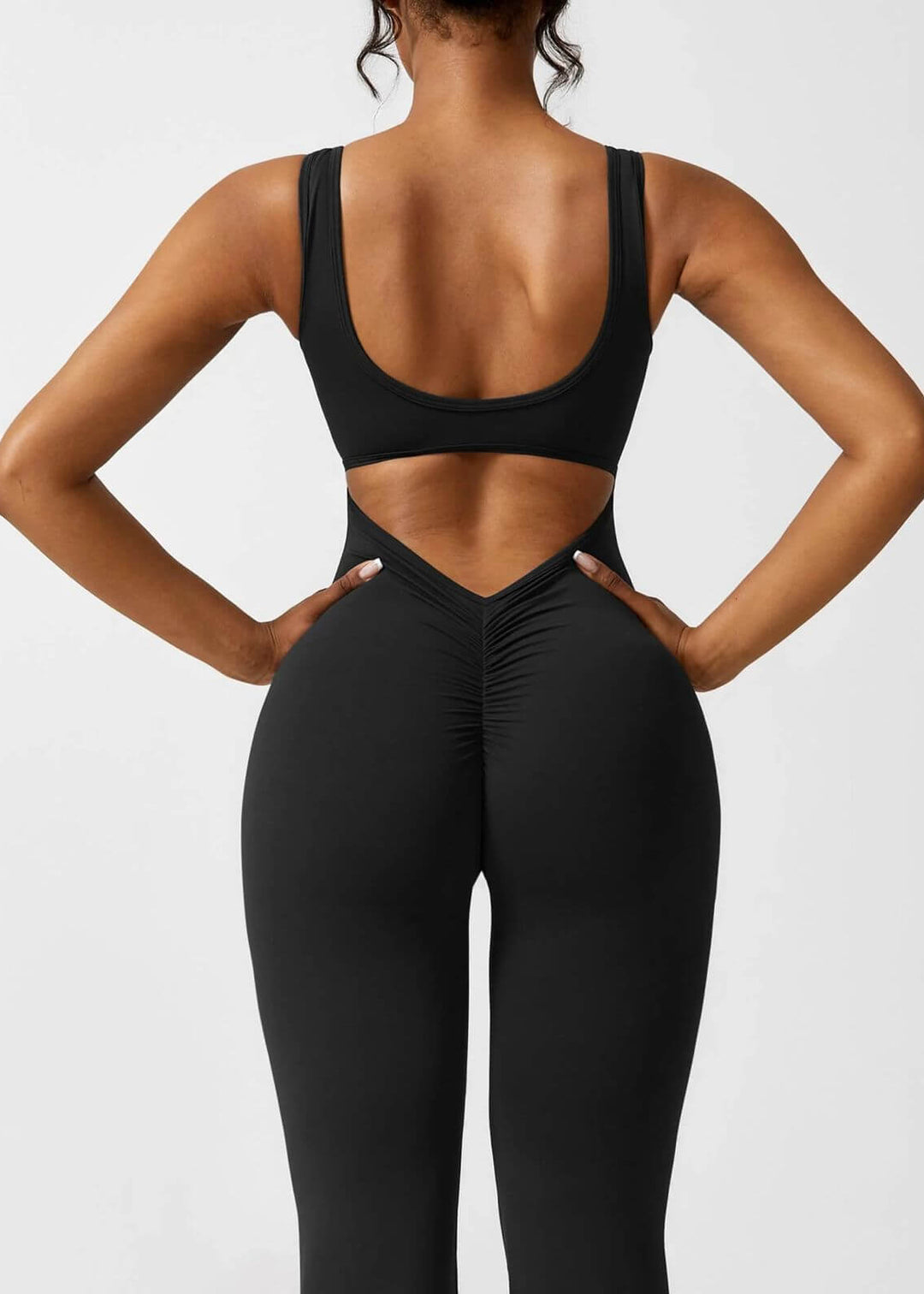 Detalle de la espalda de enterizo negro ajustado para mujer. Diseño con abertura en la espalda baja y costura con fruncido levanta cola para una horma perfecta.