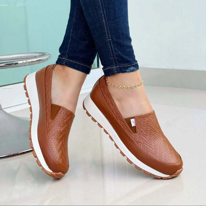 Mocasín para mujer color cuero con diseño texturizado antideslizante, suela blanca con agarre ideal para uso diario, calzado cómodo y ligero perfecto para combinar con jeans ajustados, ofrece confort y estilo casual para caminar largas distancias.