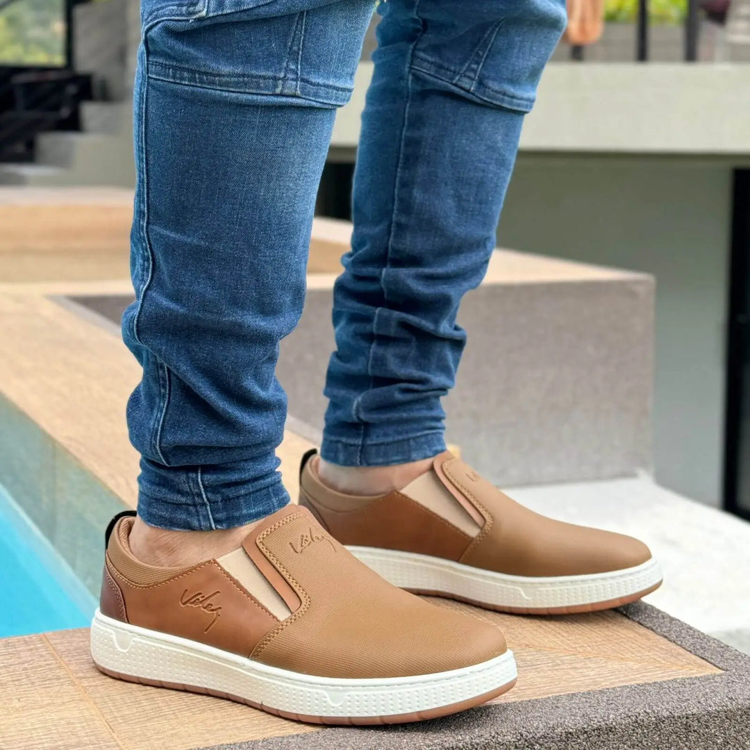 Mocasin Ebano flexibles para hombre en color marrón claro con suela blanca antideslizante, diseño slip-on cómodo y elegante perfecto para uso diario, que ofrece soporte ergonómico y material resistente para mayor durabilidad y estilo casual moderno.