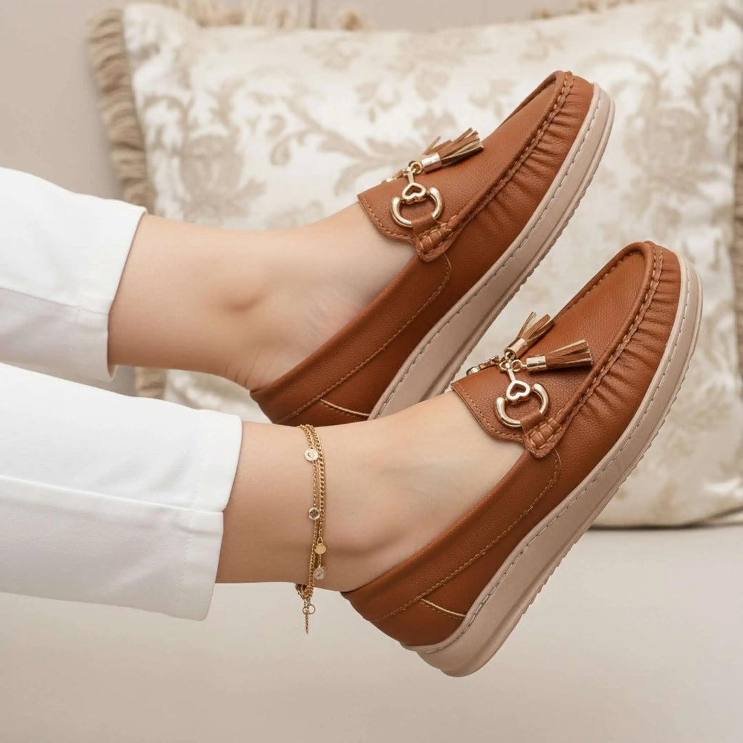 Mocasín Paloma color caramelo en piel sintética suave, diseño elegante con detalle de borlas y hebillas doradas, suela antideslizante y ligera que ofrece comodidad todo el día, perfecto para uso casual y urbano en mujeres que buscan estilo y confort en cada paso.