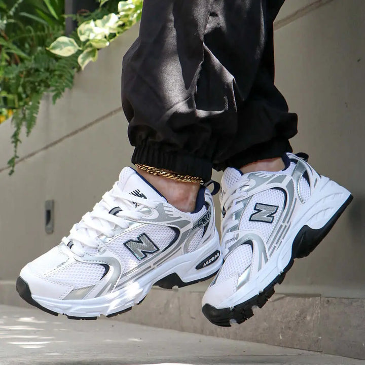 Zapatillas deportivas blancas con detalles grises y negros, diseño moderno y transpirable, suela antideslizante y amortiguación avanzada para máxima comodidad y soporte durante actividades diarias y deportivas, ideales para hombres que buscan estilo y funcionalidad.