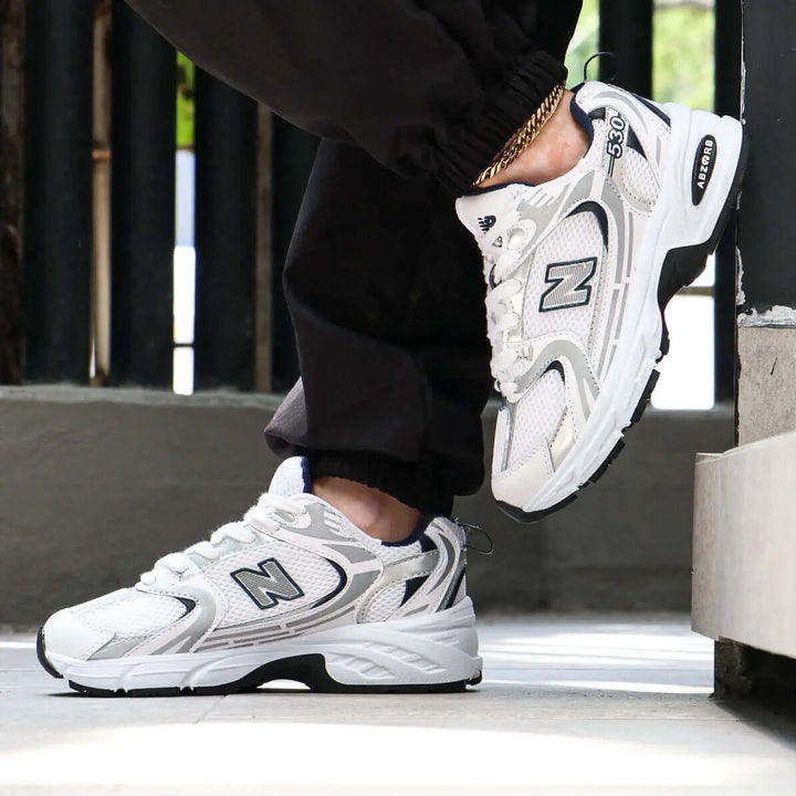 Tenis deportivos blancos con detalles grises y negros diseñados para máxima comodidad y soporte, suela antideslizante ideal para actividades diarias, calzado ligero y transpirable perfecto para uso urbano y entrenamiento, estilo moderno que combina con ropa casual, zapatillas de alta durabilidad y confort para hombres y mujeres.