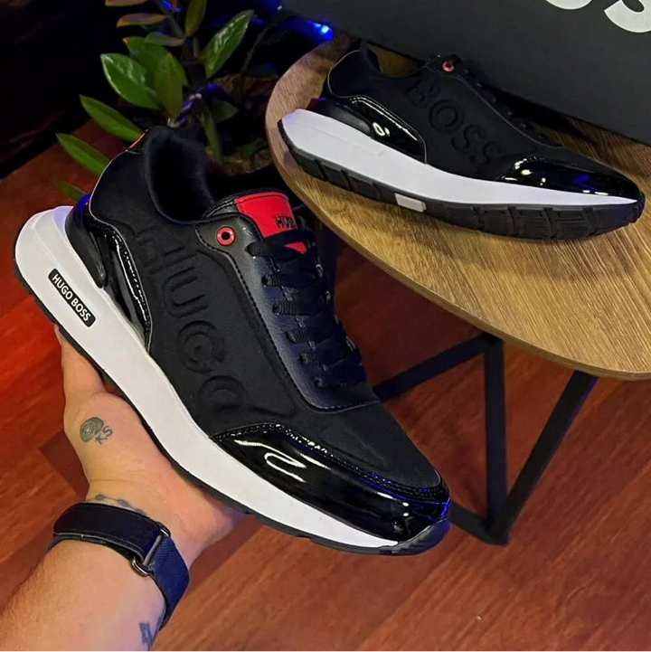 Zapatilla urbana de hombre color negro con detalles en brillo (charol) y suela tipo chunky blanca. Diseño moderno charol, urbanas, versatiles y elegantes