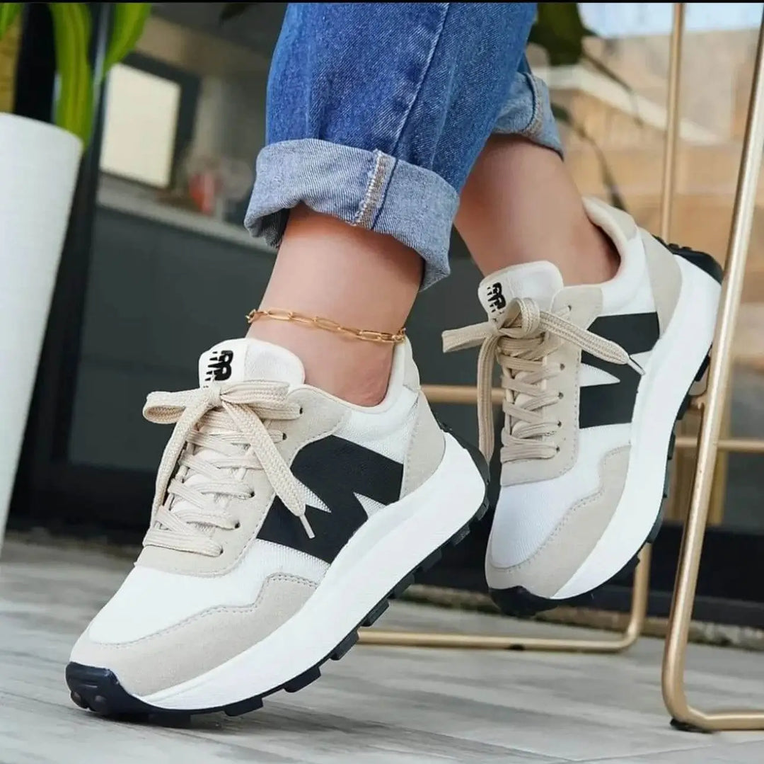 Zapatillas deportivas estilo casual color beige y blanco con detalles negros, diseño moderno y cómodo ideal para uso diario, suela antideslizante que proporciona estabilidad y soporte ergonómico para máxima comodidad y absorción de impacto, perfectas para caminar o actividades urbanas.