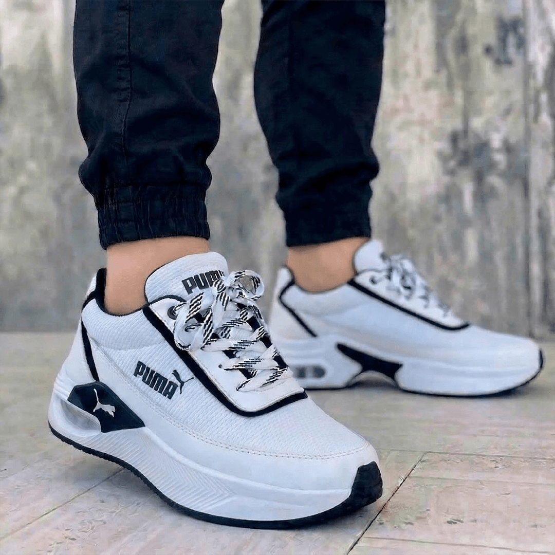 Zapatillas Puma de hombre en color blanco con plataforma y detalles en negro. Calzado casual moderno con amortiguación visible en el talón.