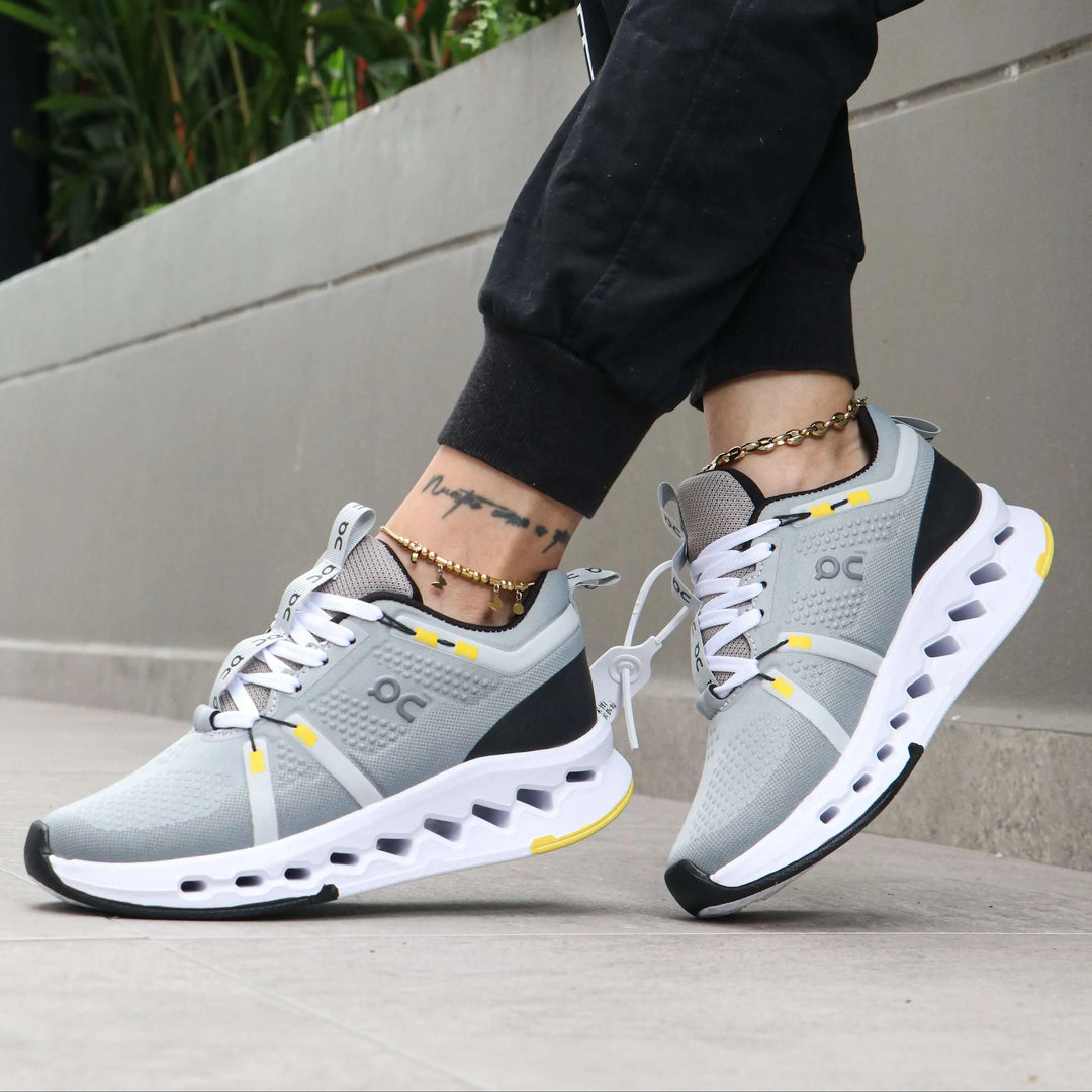 Zapatillas deportivas grises con detalles en amarillo, diseño moderno y transpirable, suela acolchonada para máxima amortiguación y confort al caminar o entrenar, ideales para correr y uso diario en ciudad.