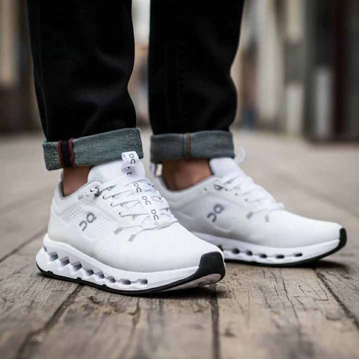 Outfit casual urbano con tenis marca On totalmente blancos y pantalón jean oscuro con doblez. Foto detallada de calzado deportivo premium en tendencia para el mercado colombiano.