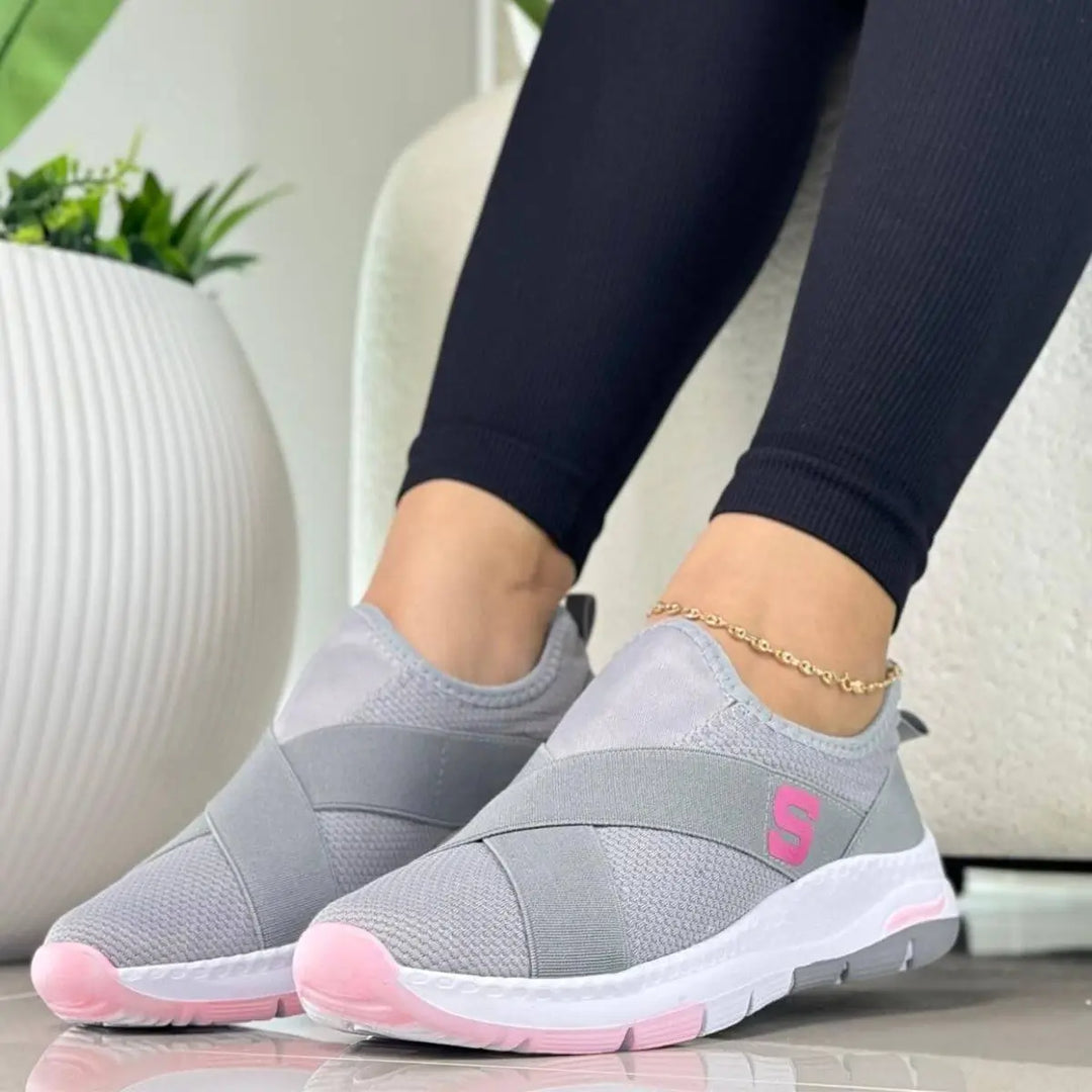 Zapatillas deportivas de mujer color gris y rosa con suela blanca, diseño slip-on con bandas elásticas cruzadas para ajuste perfecto, piso antideslizante para mayor seguridad, ideales para caminar y uso diario, calzado cómodo y ligero que ofrece amortiguación y soporte óptimo para pies sensibles.