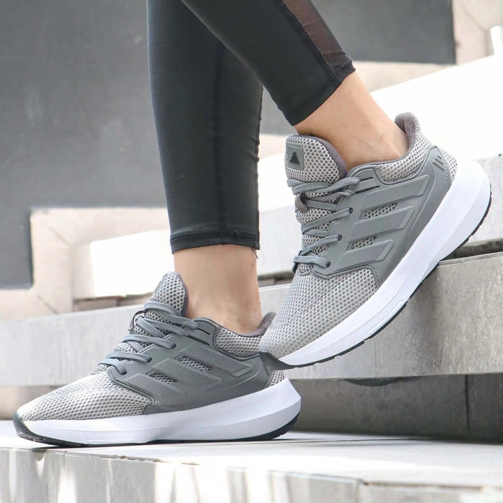 Zapatillas deportivas color gris con suela blanca antideslizante y diseño transpirable en malla, ideales para running y entrenamiento, cómodas y ligeras para uso diario, perfectas para mujer que busca estilo y desempeño en calzado deportivo.