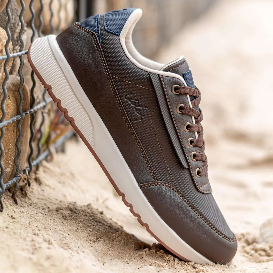 Zapato casual en tonos marrón y azul con diseño moderno y detalles en cuero sintético y tela resistente, suela blanca antideslizante y cordones marrones, ideal para uso diario cómodo y durable, perfecto para hombres que buscan estilo y confort en calzado urbano.