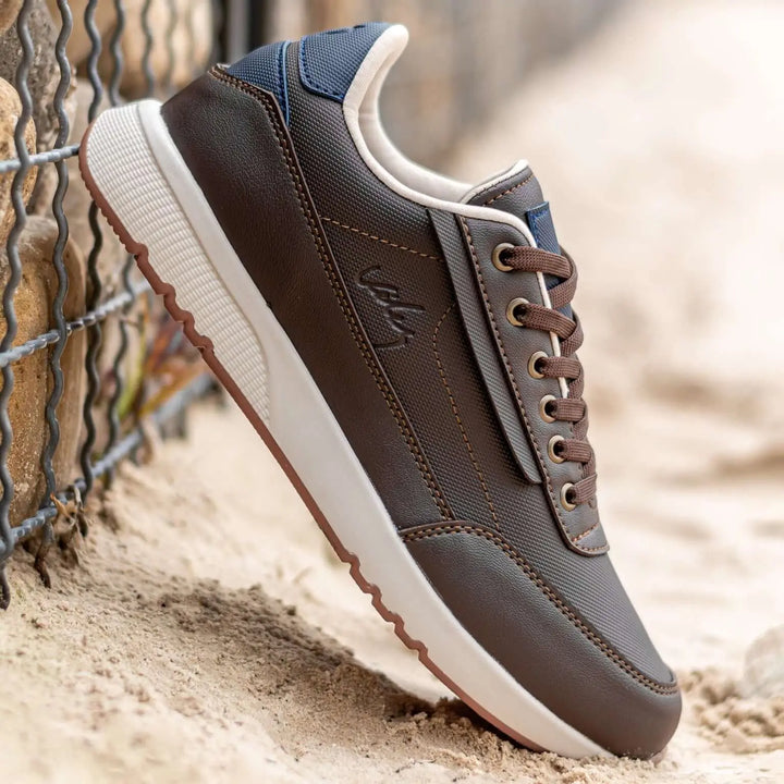 Zapato casual en tonos marrón y azul con diseño moderno y detalles en cuero sintético y tela resistente, suela blanca antideslizante y cordones marrones, ideal para uso diario cómodo y durable, perfecto para hombres que buscan estilo y confort en calzado urbano.