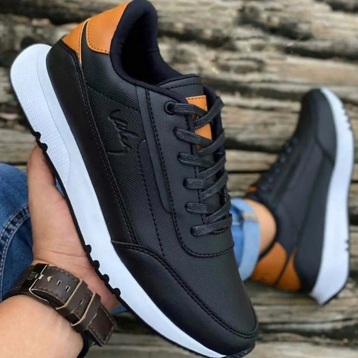 Zapatos deportivos negros con detalles en color marrón, diseño cómodo y moderno para uso casual, suela antideslizante blanca que brinda estabilidad y soporte óptimo para caminar todo el día, ideales para hombre, materiales duraderos y transpirables que garantizan confort y resistencia.