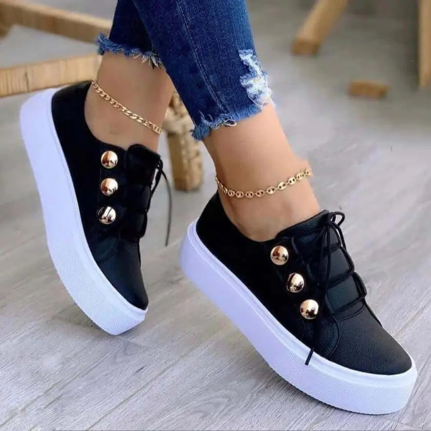 Zapatillas negras para mujer con plataforma blanca, diseño moderno y detalles metálicos dorados, ideales para uso casual y urbano, cómodas, livianas y resistentes, perfectas para combinar con jeans y ofrecer estilo y confort durante todo el día.