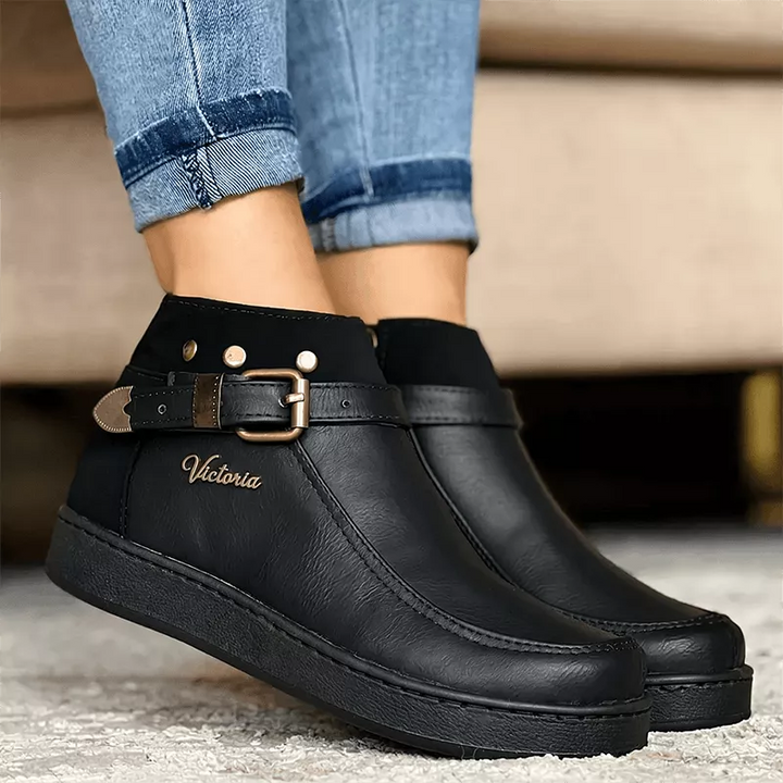 Botín negro para mujer en material sintético de alta calidad, con diseño elegante y cómodo, suela antideslizante ideal para uso diario, cierre lateral y detalle de hebilla decorativa que aporta estilo sofisticado, perfecto para combinar con jeans o pantalones casuales.