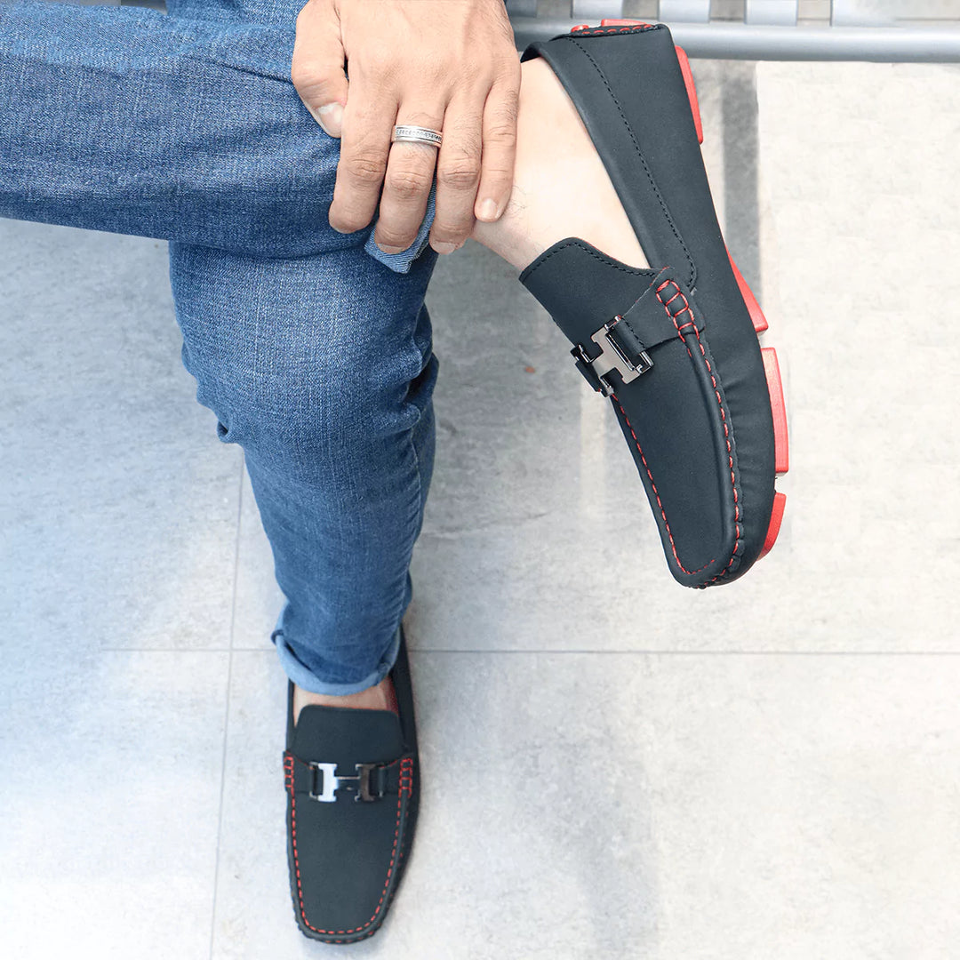 Mocasín Heritage urbanos masculinos en color negro con detalles en costura roja, diseño cómodo y moderno ideal para uso diario, suela antideslizante que brinda estabilidad y seguridad, perfectos para combinar con jeans y outfits casuales, calzado duradero y versátil que ofrece confort y estilo en cada paso.