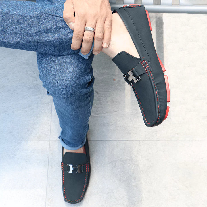 Mocasín Heritage urbanos masculinos en color negro con detalles en costura roja, diseño cómodo y moderno ideal para uso diario, suela antideslizante que brinda estabilidad y seguridad, perfectos para combinar con jeans y outfits casuales, calzado duradero y versátil que ofrece confort y estilo en cada paso.