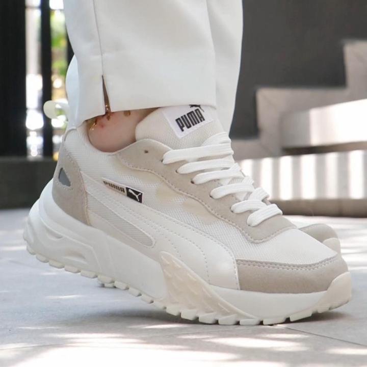 Video mostrando las Zapatillas Street Rise para mujer, con toma inicial del calzado en mano y luego en los pies mientras la modelo camina y baja las escaleras, destacando la suela gruesa con amortiguación, el diseño urbano en color beige y blanco y el estilo moderno y cómodo ideal para uso diario.