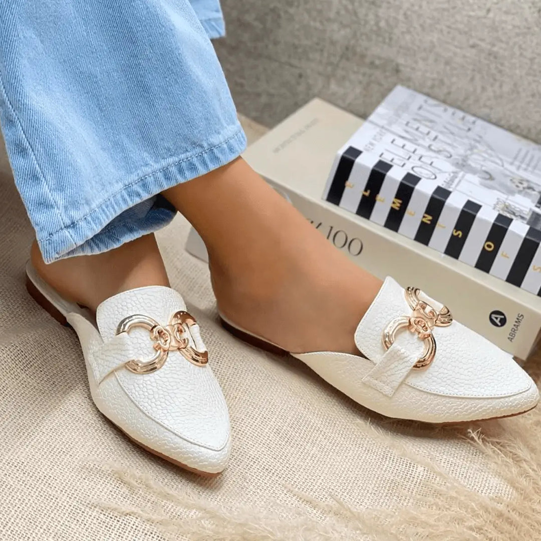 Sandalias suecas elegantes color blanco con detalle metálico dorado, diseño cómodo y moderno ideal para uso diario, plantilla suave y suela antideslizante para mayor estabilidad, perfectas para combinar con jeans y outfits casuales en climas cálidos.