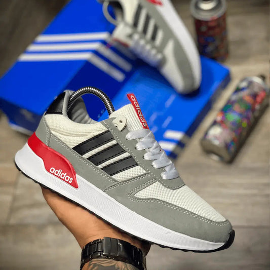 Tenis deportivo ZX500 en tonos gris, blanco y rojo con suela blanca ligera, diseño moderno ideal para uso diario, proporciona confort, flexibilidad y soporte para caminar y correr, calzado casual resistente y transpirable para estilo y comodidad.