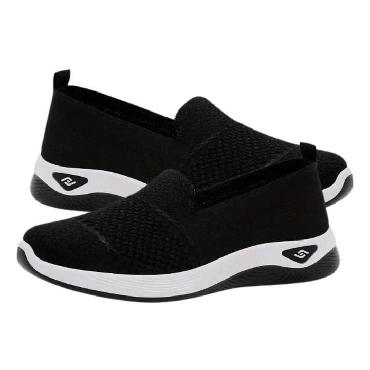 Zapatillas deportivas livianas color negro con diseño transpirable en tejido mesh, suela antideslizante blanca y negra, calzado cómodo ideal para uso diario, fácil de poner gracias a su ajuste slip-on, perfectas para caminar y actividades casuales manteniendo frescura y soporte en los pies.