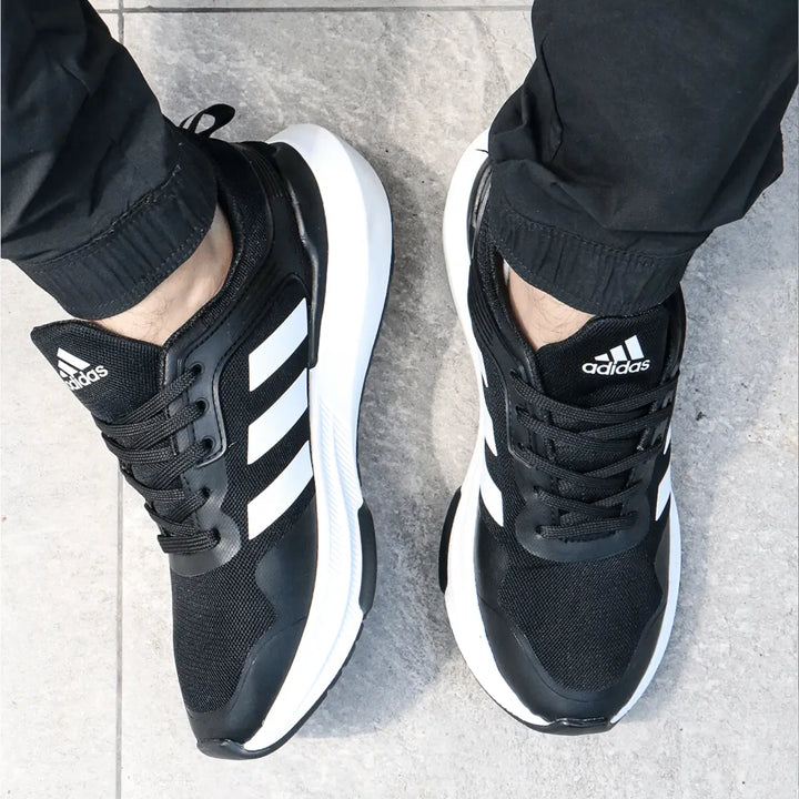 Tenis deportivo negro con detalles blancos, diseño ergonómico y suela antideslizante, ideal para correr y uso diario, ofreciendo comodidad y soporte óptimo para el pie.