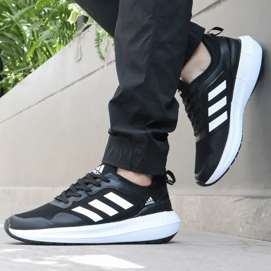Tenis deportivo para correr color negro con detalles blancos, diseño ligero y cómodo, suela antideslizante que garantiza estabilidad y amortiguación óptima para entrenamientos y actividades diarias.